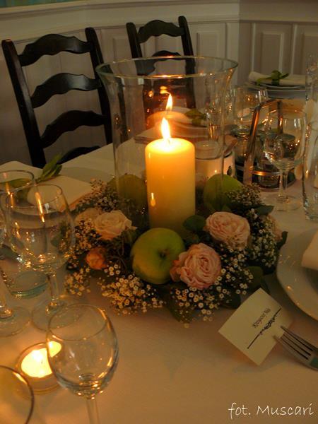 gipsówka, róże, jabłka i lampion na stole