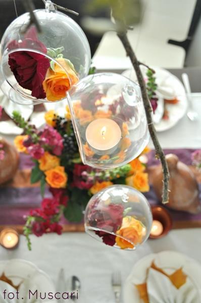 kwiaty i świece w wiszących nad stołem szklanych bańkach