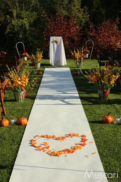 miejsce na ślub w plenerze - kwiaty, dynie i płatki kwiatów na białym dywanie