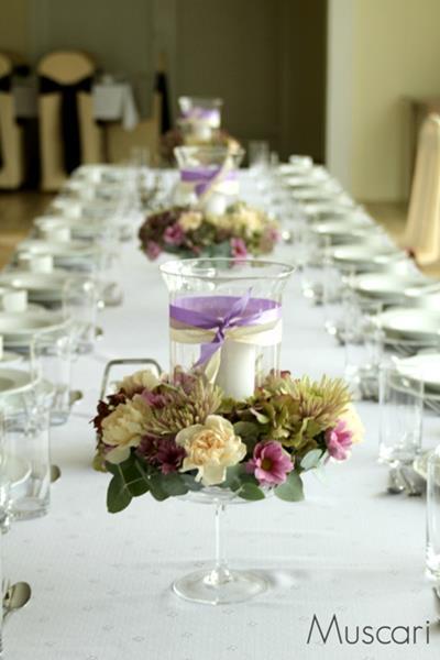 wianki z kwiatów hortensji, goździków, chryzantem i zieleni z lampionami na stole podczas wesela