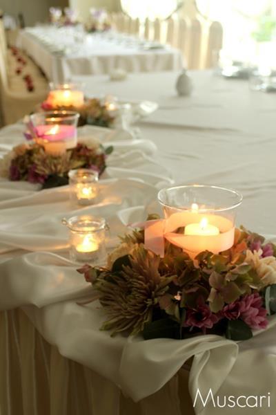 wianki z kwiatów z lampionami i świece na stole pary młodej