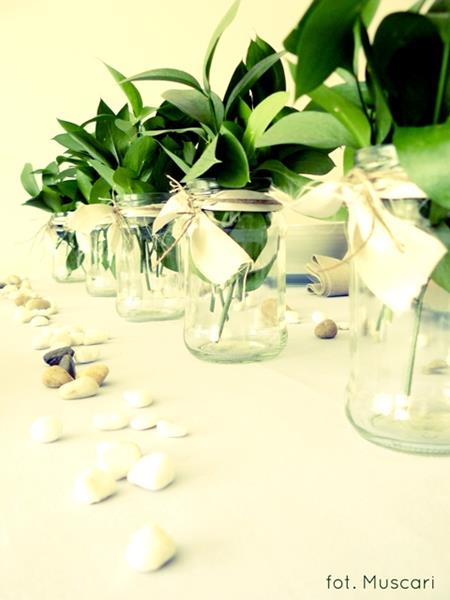 zielone liście w słoikach i kamyczki w dekoracji stołu