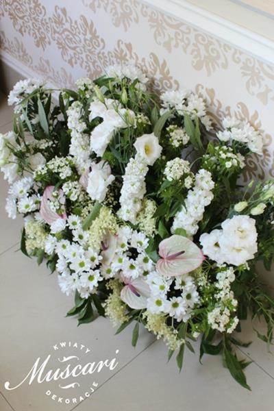 wiązanka z kwiatów i zieleni przed ołtarzem podczas ślubu