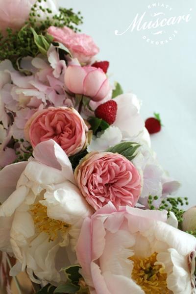 różowe piwonie, róże, hortensje. goździki, zieleń i truskawki w wiązance na stole pary młodej