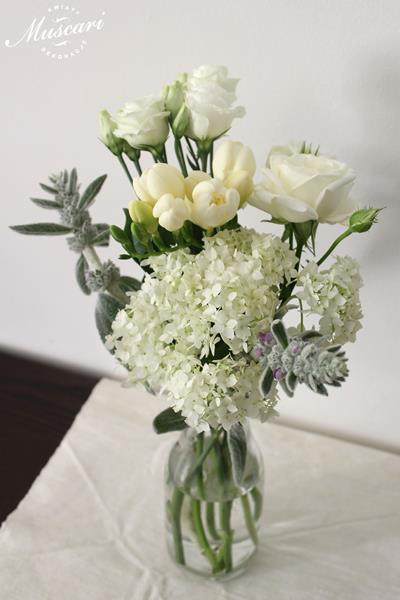 białe kwiaty w butelce - róże, frezje, hortensje i eustomy