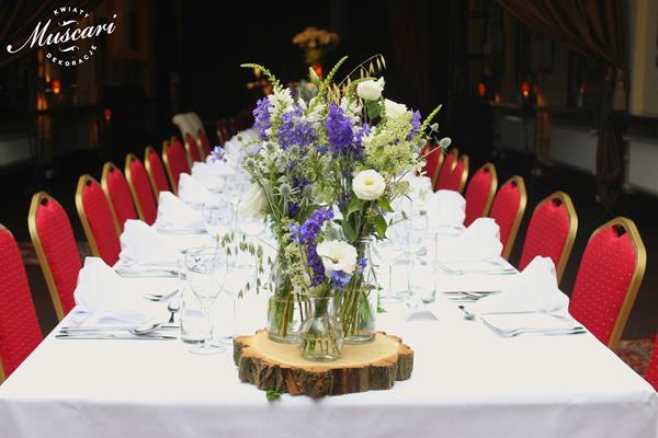 kwiaty w bukietach na podstawce z drewna na stole na weselu