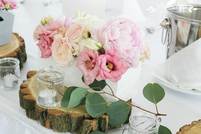 stół pary młodej ozdobiony pastelowymi kwiatami, zielenią, drewnem i lampionami