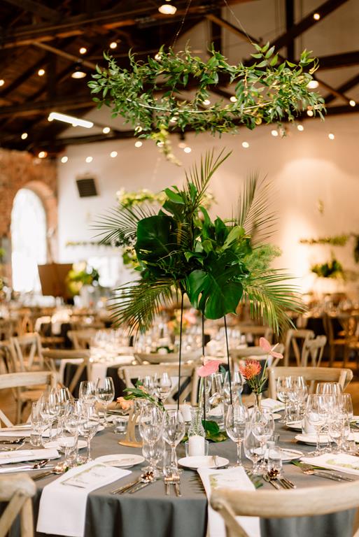 egzotyczne kwiaty, intensywna zieleń liści monstery i latający zielony wianek - dekoracja stołu na wesele