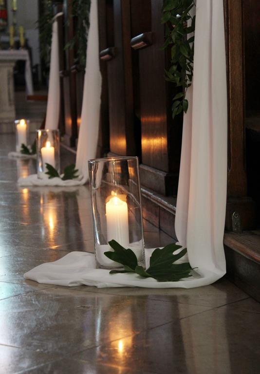liście monstery i białe świece - dekoracja kościoła na ślub