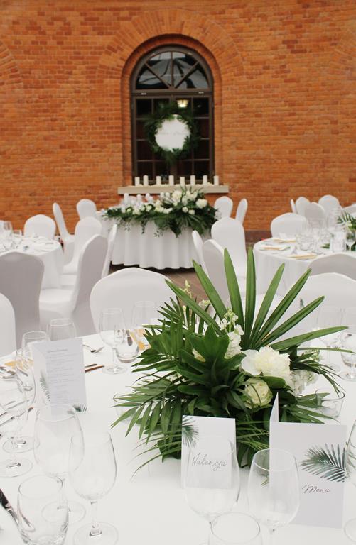 stoł pary młodej w tle - dekoracja kwiatowa na pierwszym planie
