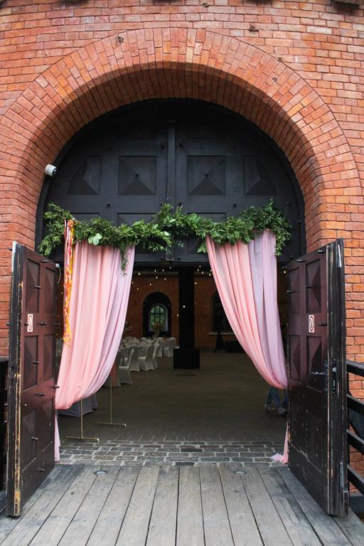 kolorowe wesela forteca - wejście udekorowane zieloną girlandą i tkaniną