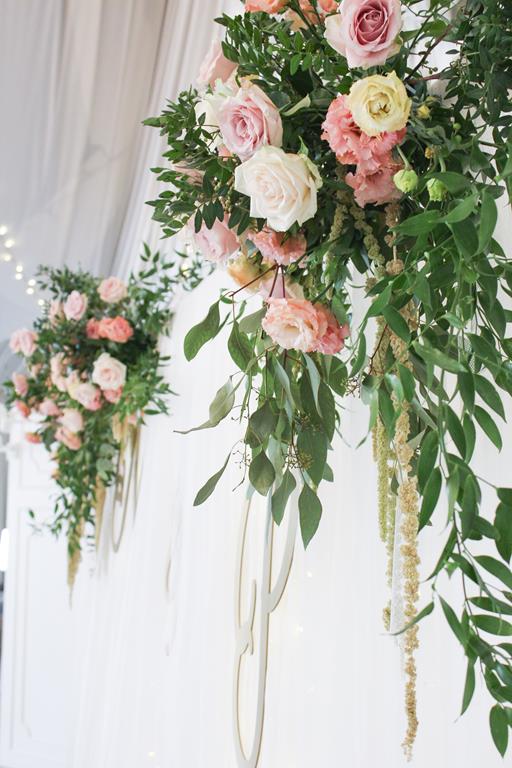 romantyczne wesele w Rezydencji Miętowe Wzgórza - kwiaty i zieleń na ściance za stołem pary młodej