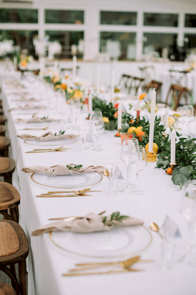 podłużny stół na weselu - dekoracja w formie zielonej girlandy ozdobionej kolorowymi kwiatami i owocami