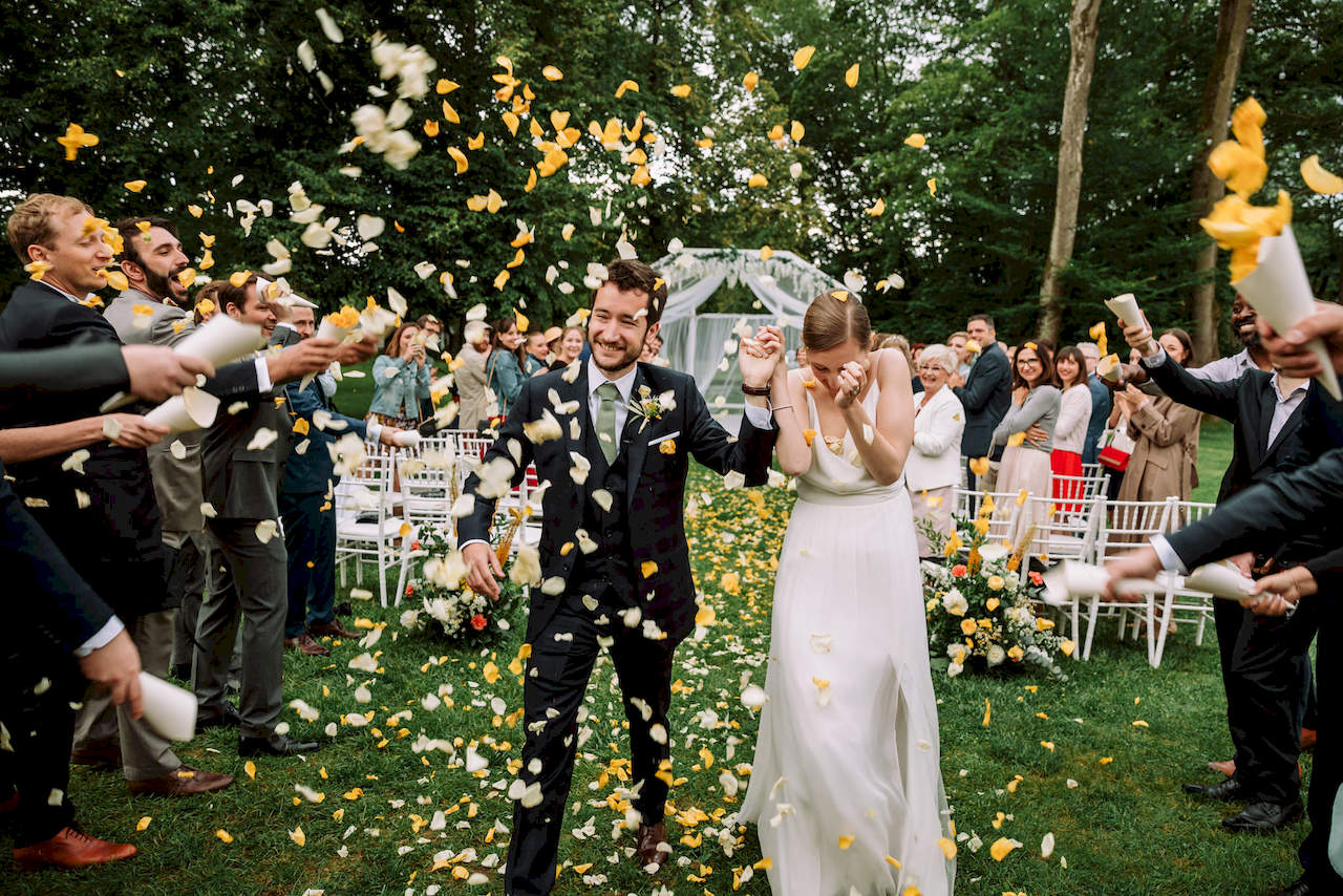 Para młoda obsypywana płatkami kwiatów z rożków kwiatowych tuż po zakończeniu ceremonii ślubnej.